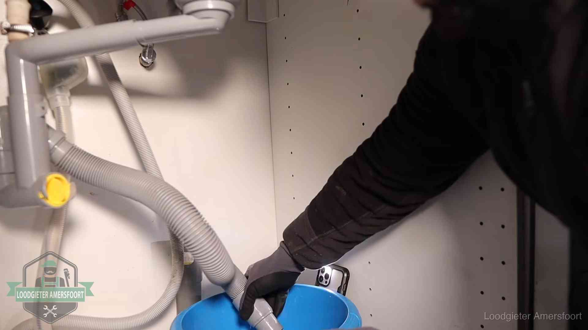 Afvoerslang loopt leeg in een emmer onder de gootsteen in Amersfoort, een klus die je zelf kunt doen