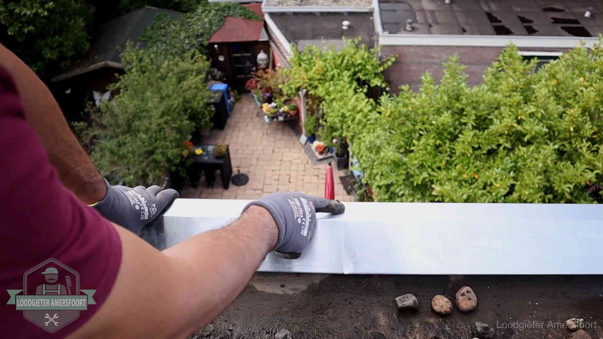 Vakman plaatst een daktrim op de dakrand van een woning in Amersfoort