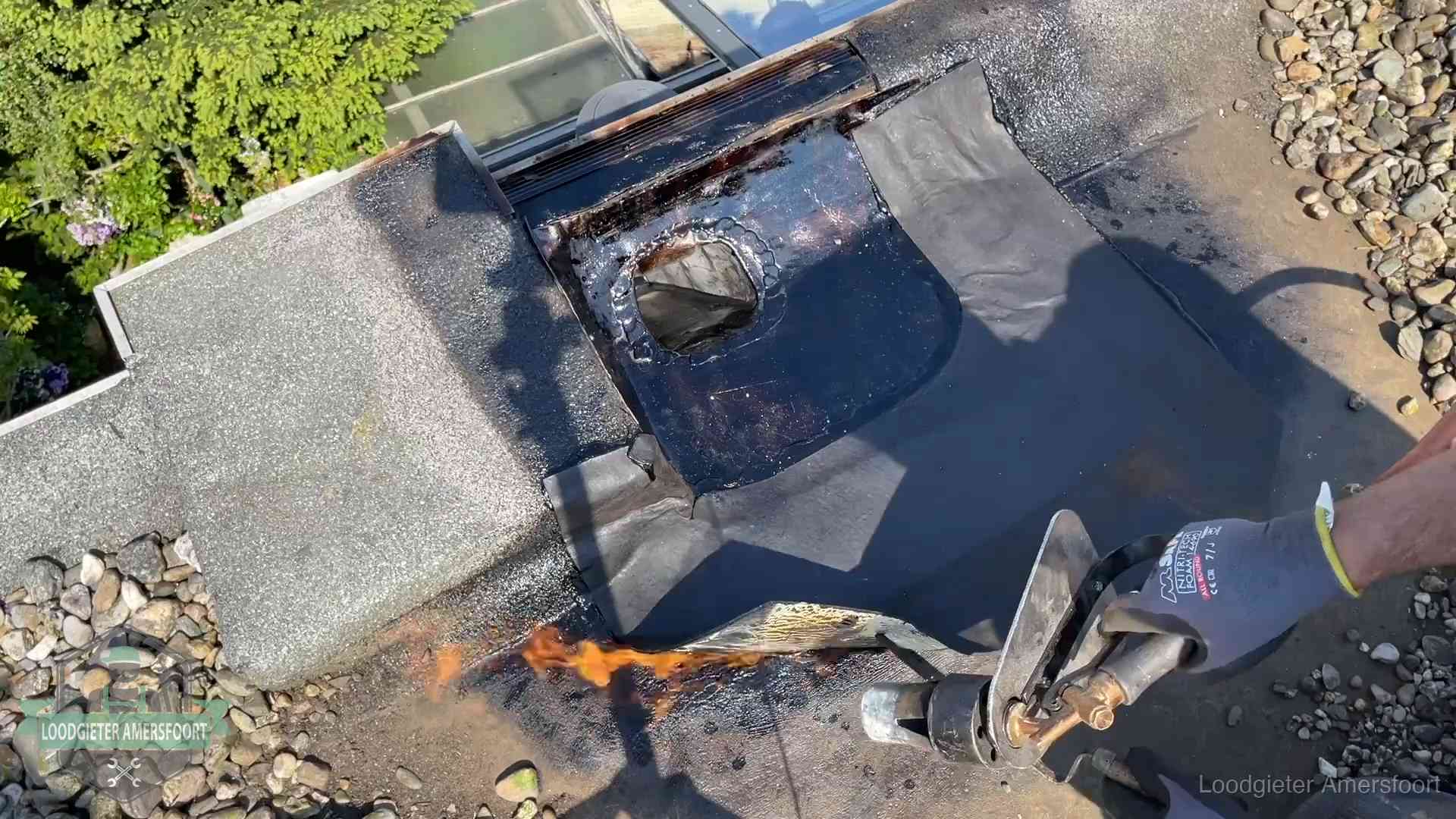 Dakdekker brandt bitumen rond een doorvoer tijdens een daklekkage-reparatie in Amersfoort