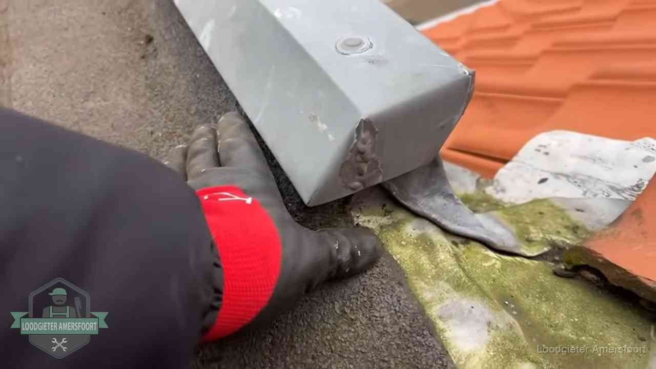 Controle van een zinken hemelwaterafvoer met loodslab bij dakpannen in Amersfoort