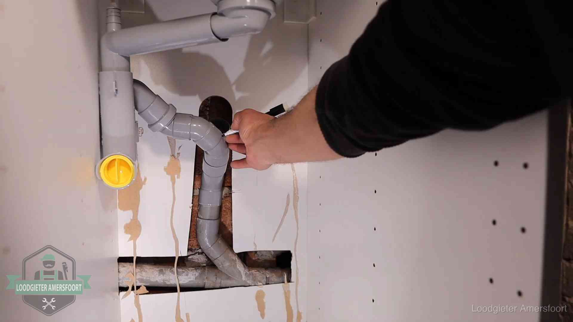 Loodgieter voor verhuurders en bedrijven in Amersfoort Loodgieter markeert een pvc-afvoerbuis onder een gootsteen in Amersfoort