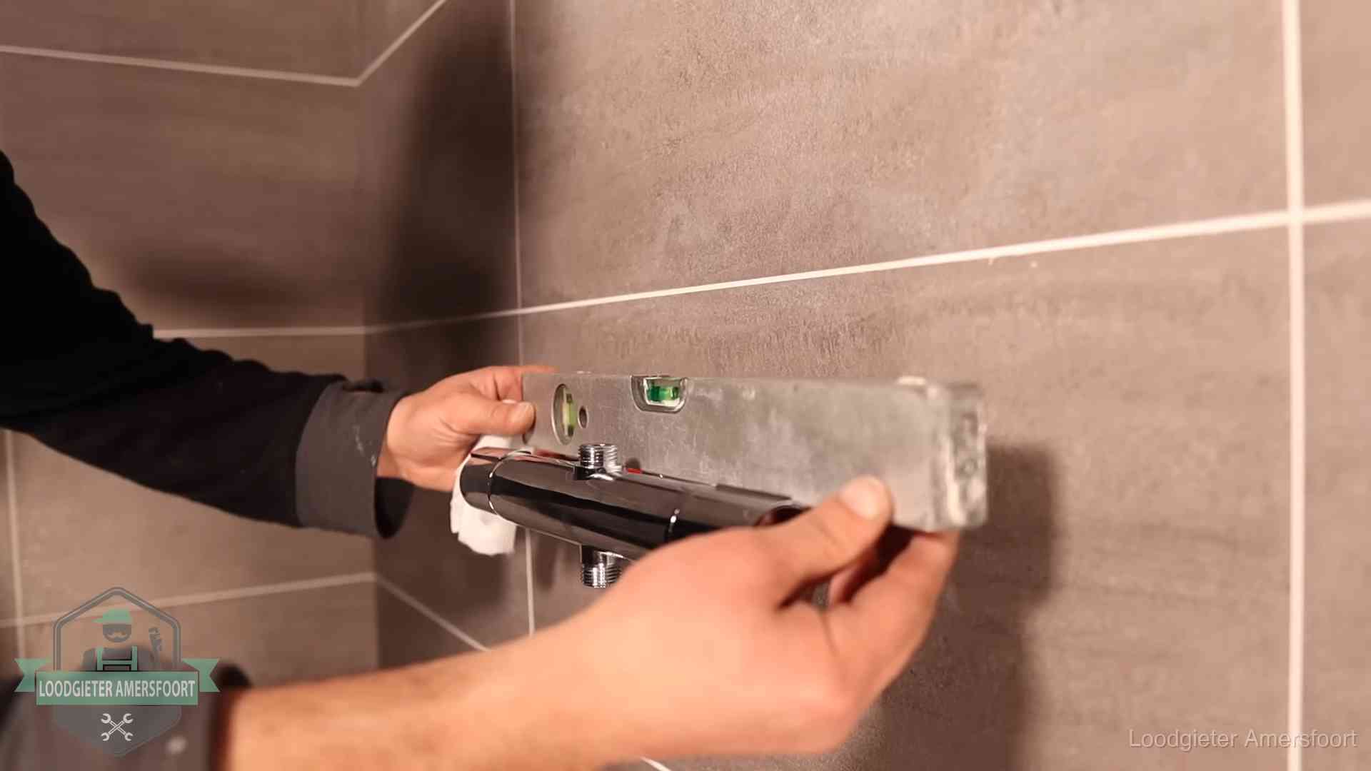 Loodgietersbedrijf voor sanitair in Amersfoort Loodgieter lijnt een douchekraan uit met een waterpas in een woning in Amersfoort