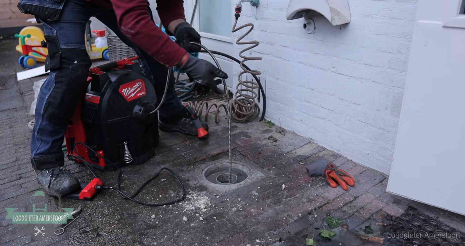 Ontstoppingsputje in de bestrating naast de gevel van een woning in Amersfoort