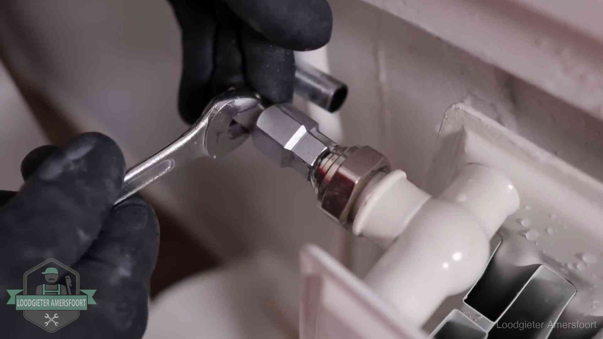 Steeksleutel draait een wartelkoppeling op een radiatorkraan aan in Amersfoort