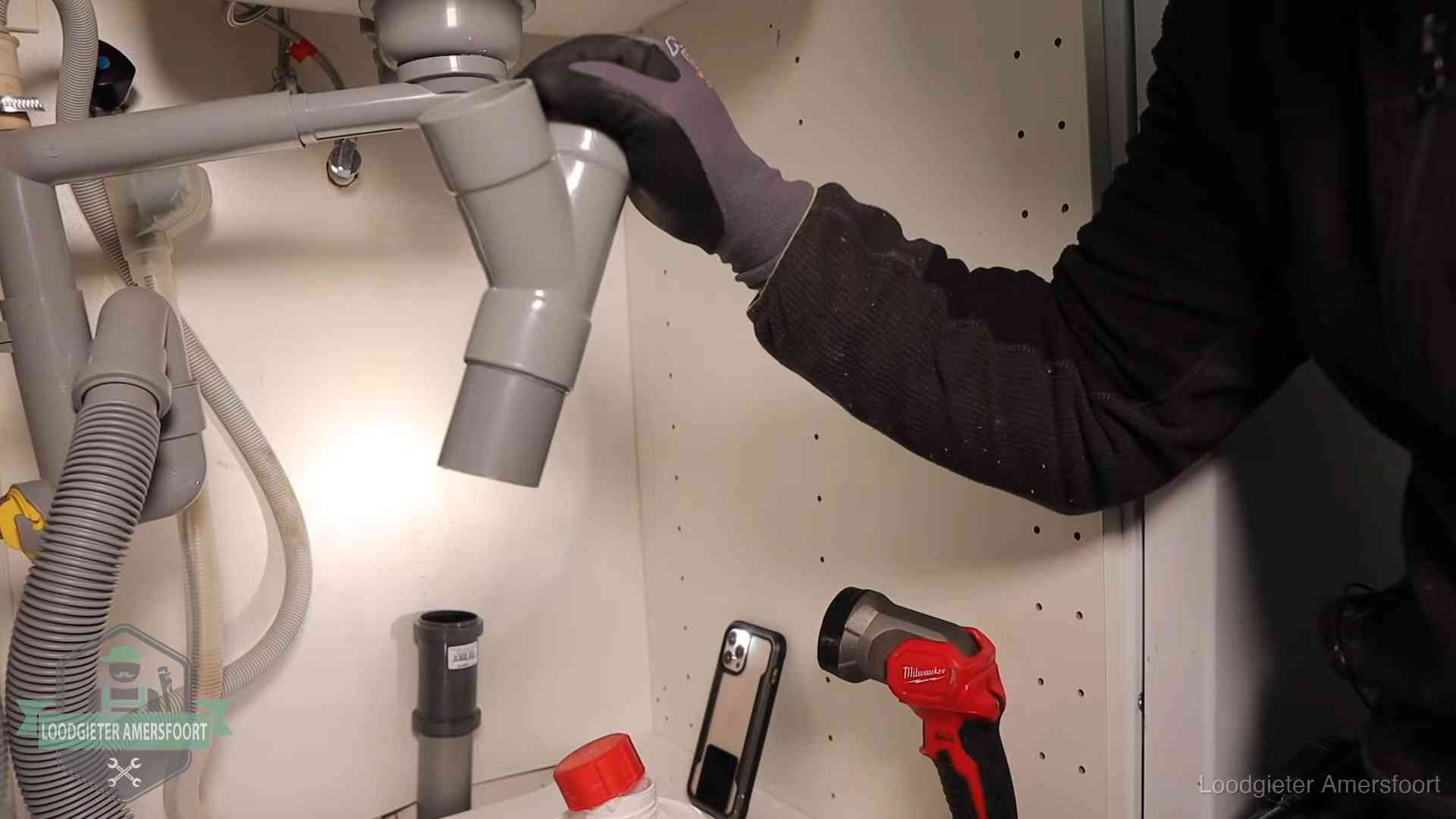 Loodgieter demonteert het sifon- en afvoerwerk onder een gootsteen in Amersfoort bij stankklachten