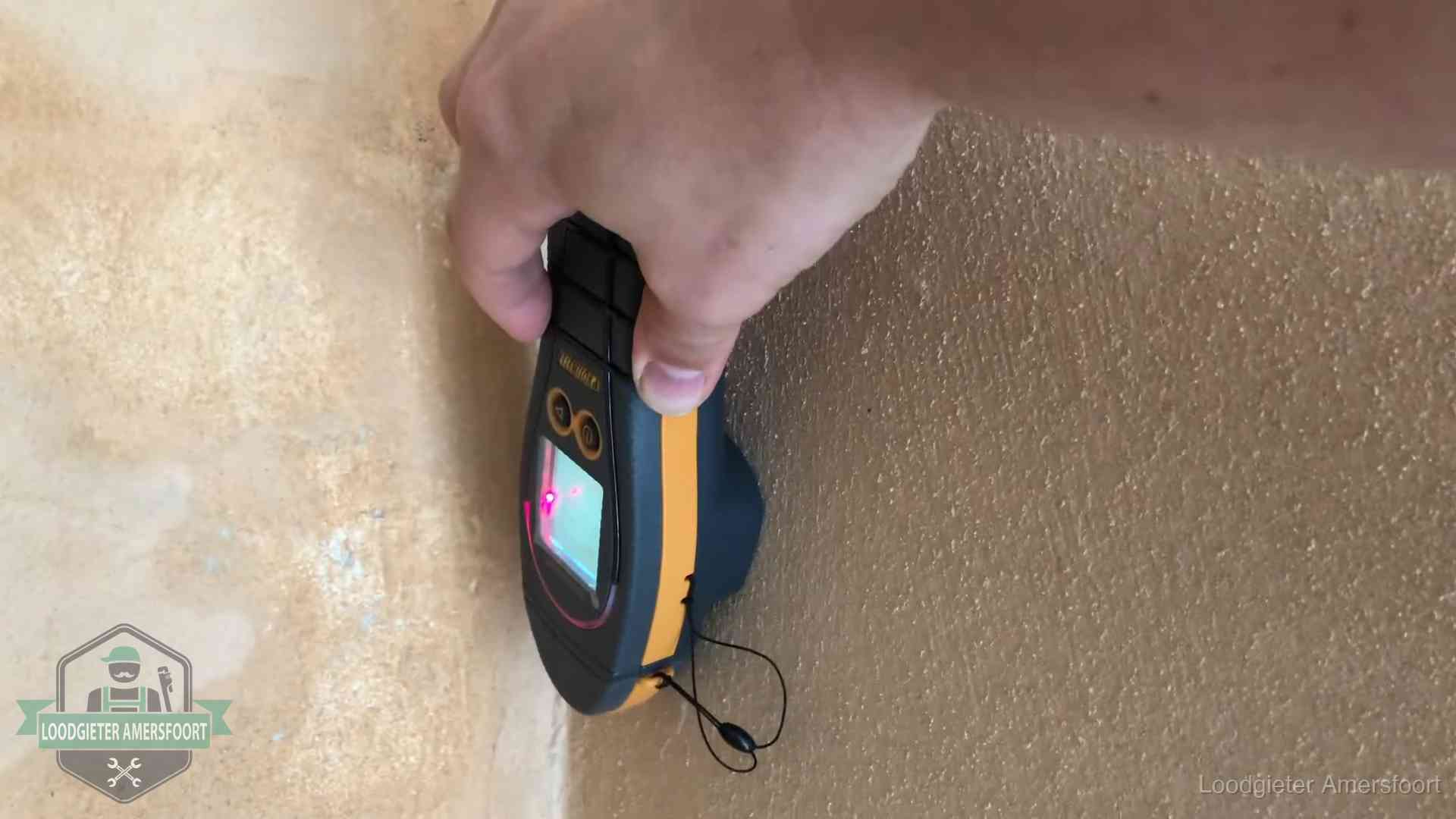 Vochtmeter tegen een muur met vochtplekken tijdens het opsporen van een daklekkage in Amersfoort